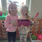 dwie dziewczynki stoja przy parapecie z napisem Zielony kacik i prezentuja przygotowane doniczki.jpg